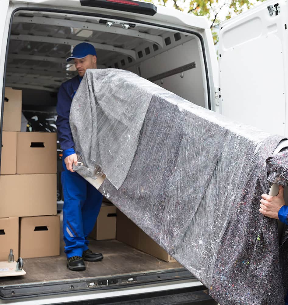 Zwei Männer entladen ein großes Möbelstück aus einem Lieferwagen.