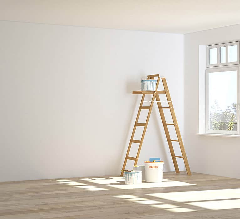 Leerer Raum mit einer Leiter und einem Farbkübel in der Ecke.